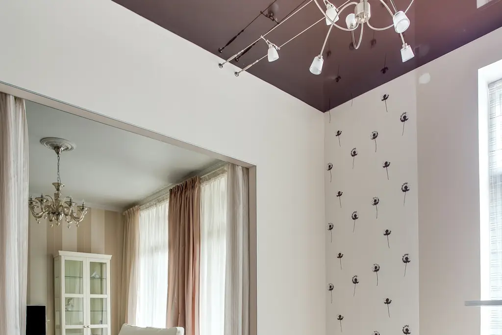 Salle à manger sous un plafond tendu laqué qui reflète la pièce, suspension à branches